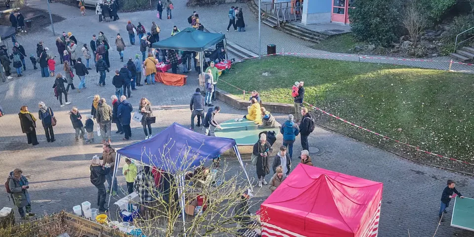 Viele Menschen besuchen Stände und treffen sich auf dem Schulhof während eines Adventsfests der Rudolf-Steiner-Schule.