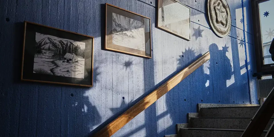 Treppenhaus der Rudolf-Steiner-Schule mit Bildern an der Wand und Sternschatten im Sonnenlicht.