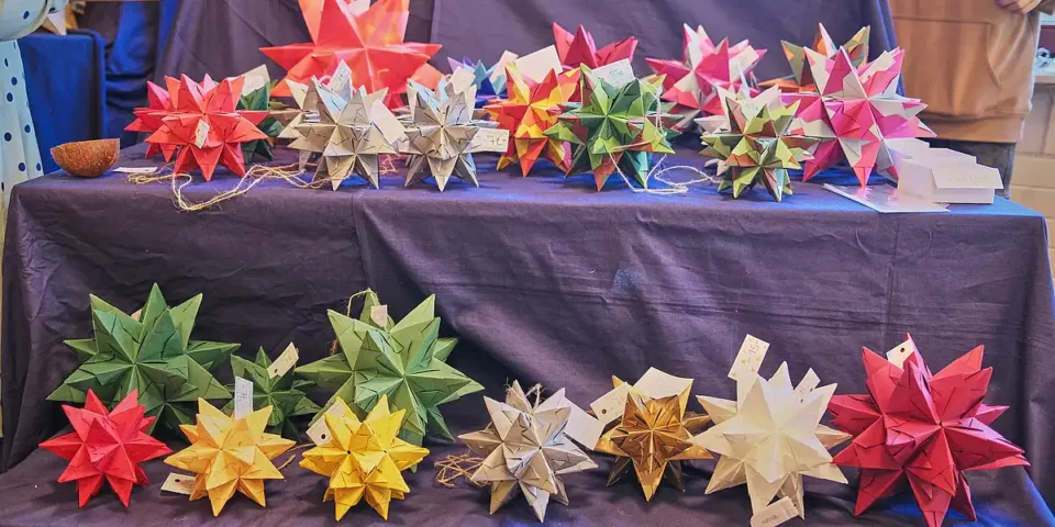 Bunte, handgefaltete Papiersterne liegen auf einem Tisch zum Verkauf beim Adventsfest der Rudolf-Steiner-Schule.