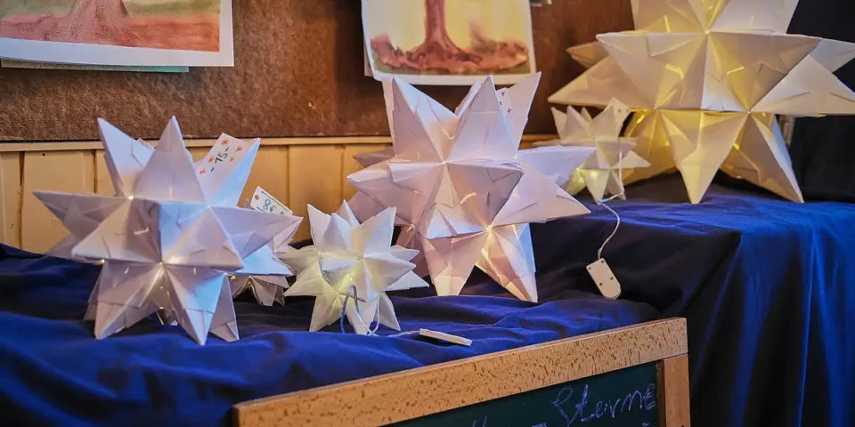 Leuchtende, handgefaltete Papiersterne auf einem Tisch beim Adventsfest der Rudolf-Steiner-Schule.