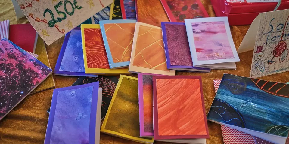 Bunte handgemachte Karten liegen auf einem Tisch mit Preisschild.