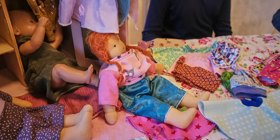 Handgemachte Stoffpuppen und Kinderkleidung auf einem Verkaufstisch.