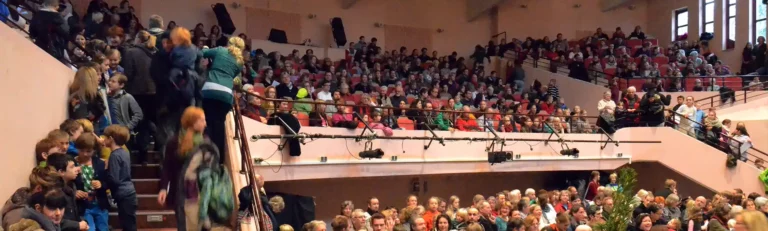 Publikum sitzt im Festsaal bei einer Schulveranstaltung.