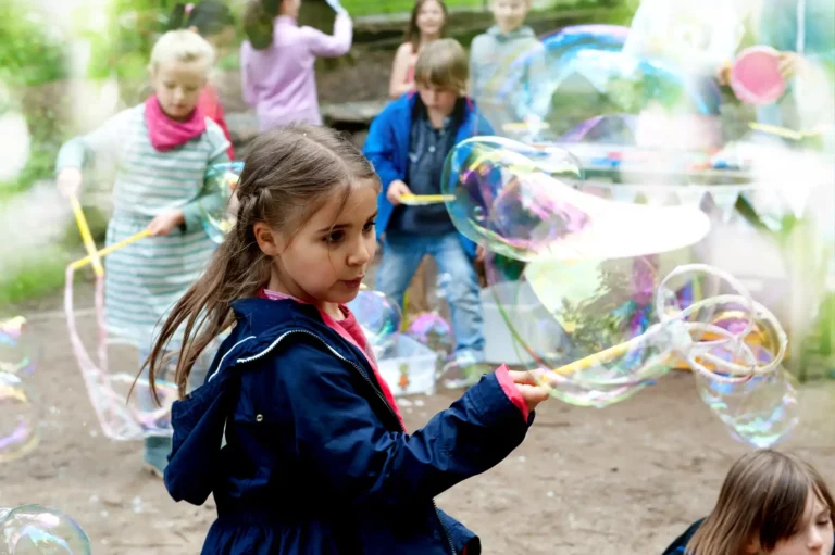 Kinder spielen gemeinsam mit großen Seifenblasen im Freien.