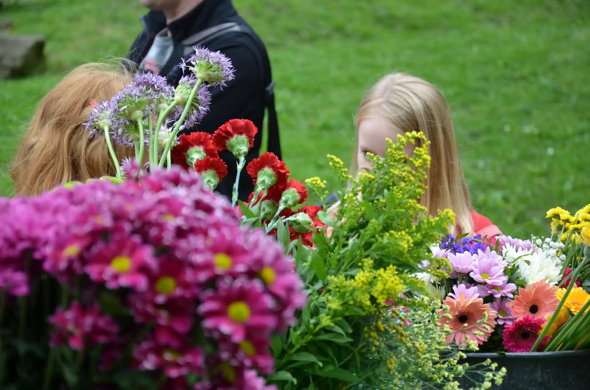 Kinder betrachten und arrangieren Blumen bei einer Schulaktivität im Freien.