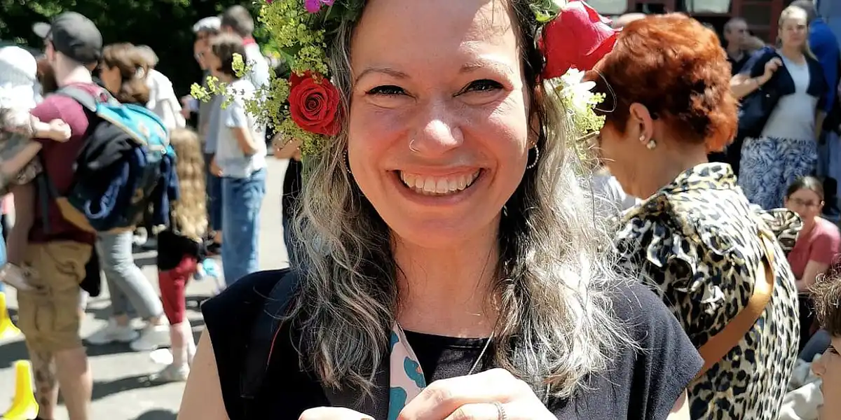 Lächelnde Frau mit Blumen im Haar auf einem Sommerfest.