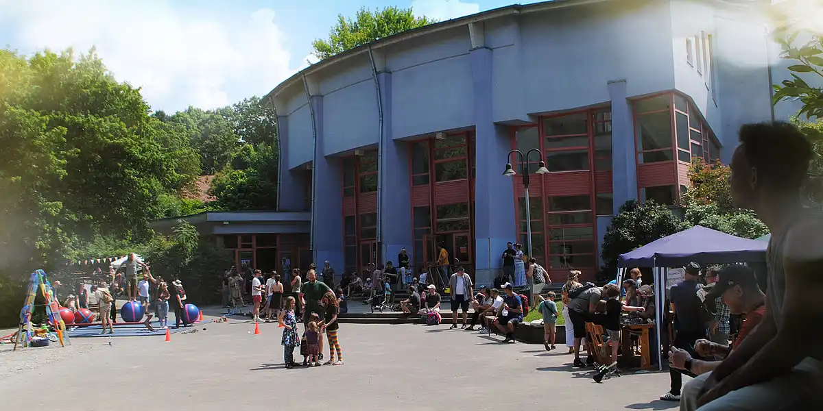 Menschen besuchen ein Sommerfest vor dem Schulgebäude.