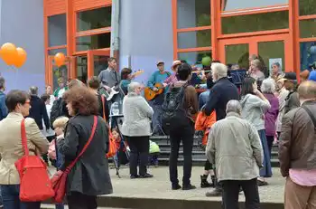 Menschen versammeln sich bei einer Schulveranstaltung vor dem Gebäude.