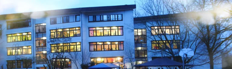 Beleuchtetes Schulgebäude am Abend im Winter.